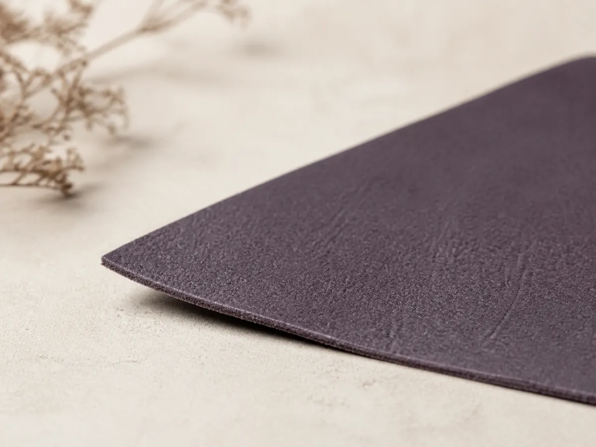 Close-up of grape-residue based vegan leather swatch showing fine aubergine matte grain